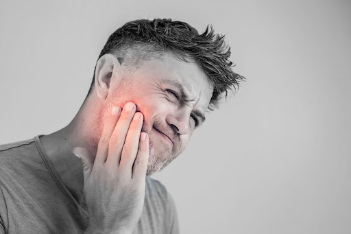 A man grimacing in pain from a cavity. 