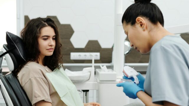 Dentist reviewing dental structure with a plastic teeth model for patient understanding
